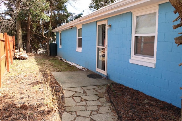 exterior space featuring concrete block siding and fence