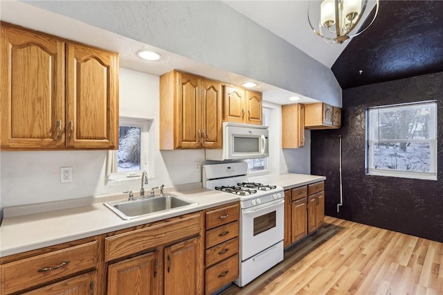kitchen with light countertops, a sink, white appliances, and lofted ceiling