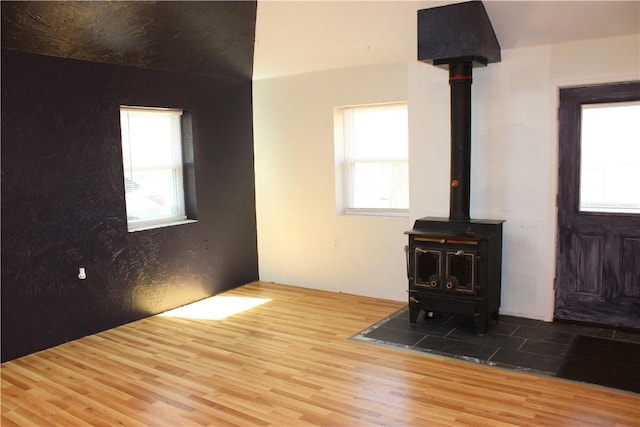 unfurnished living room with wood finished floors, a wealth of natural light, and a wood stove