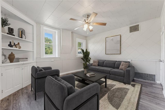 living area featuring a ceiling fan, visible vents, wood finished floors, and baseboards