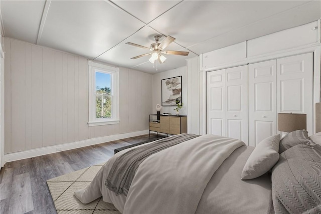 bedroom featuring baseboards, wood finished floors, a ceiling fan, and a closet