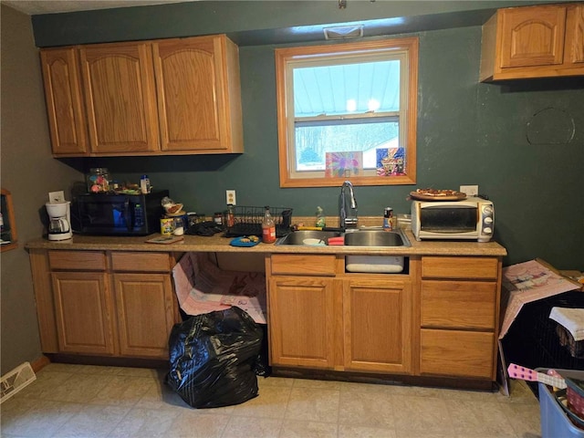 104 Forrest St, Petrolia, PA 16050 - kitchen with light countertops, a sink, black microwave, brown cabinetry, and visible vents