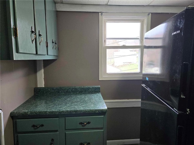 104 Forrest St, Petrolia, PA 16050 - interior space featuring freestanding refrigerator, green cabinetry, dark countertops, and a drop ceiling