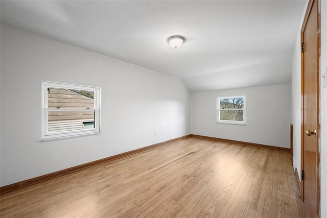 additional living space with light wood-type flooring, baseboards, and vaulted ceiling