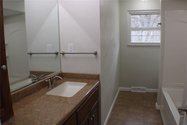 bathroom with baseboards, vanity, a bath, and tile patterned flooring