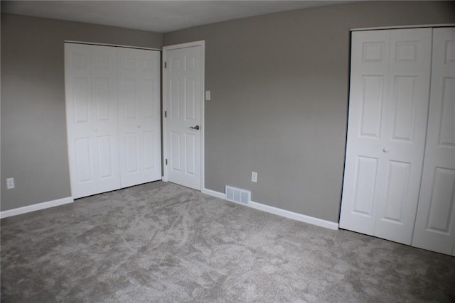 unfurnished bedroom with carpet, baseboards, and multiple closets