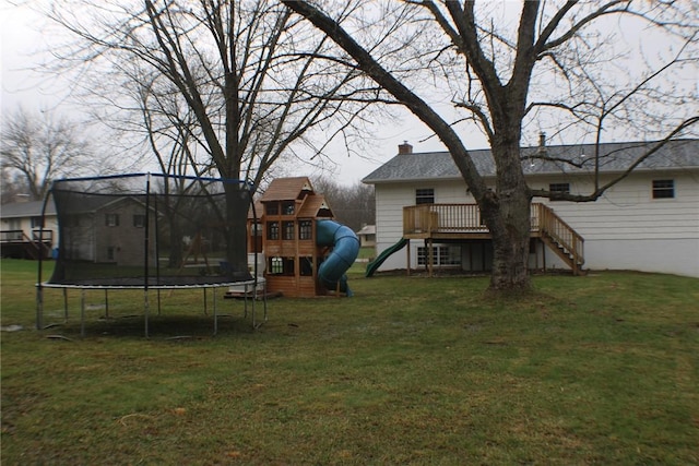 view of grassy yard with a trampoline, a playground, stairs, and a wooden deck