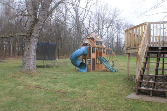 view of play area with a trampoline, a lawn, and a wooden deck