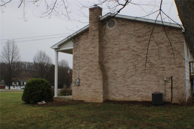 view of side of property with a chimney, a yard, and brick siding