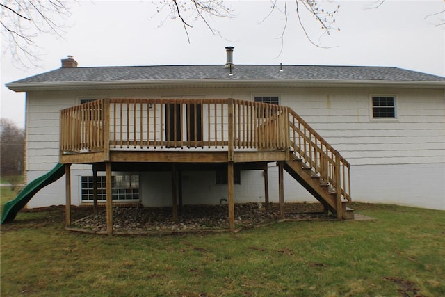 back of property with a chimney, a yard, a wooden deck, and roof with shingles