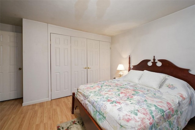 bedroom featuring baseboards, light wood-type flooring, and a closet