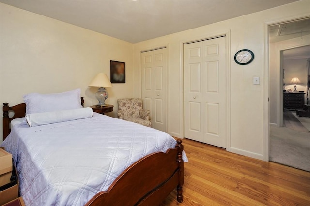bedroom with baseboards, light wood-style floors, and multiple closets