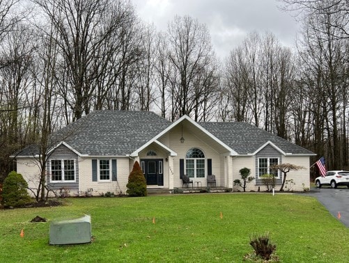 single story home with a front lawn and covered porch