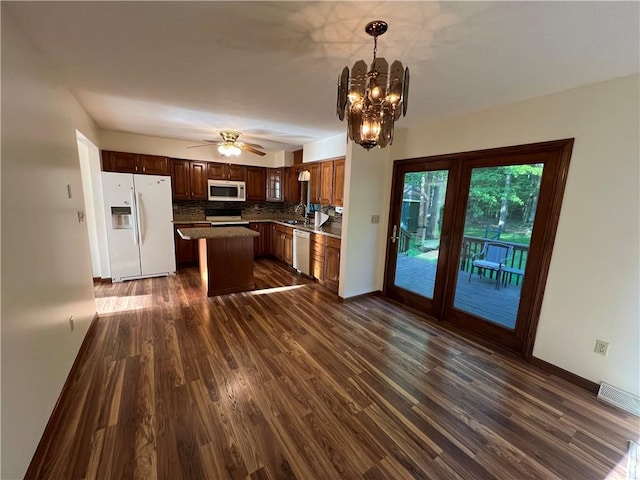 kitchen with white appliances, dark wood finished floors, a chandelier, ceiling fan, and backsplash