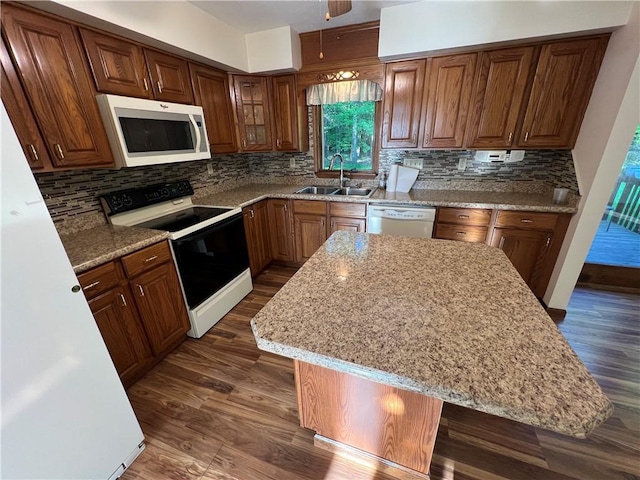 kitchen with white appliances, a sink, and dark wood-style floors