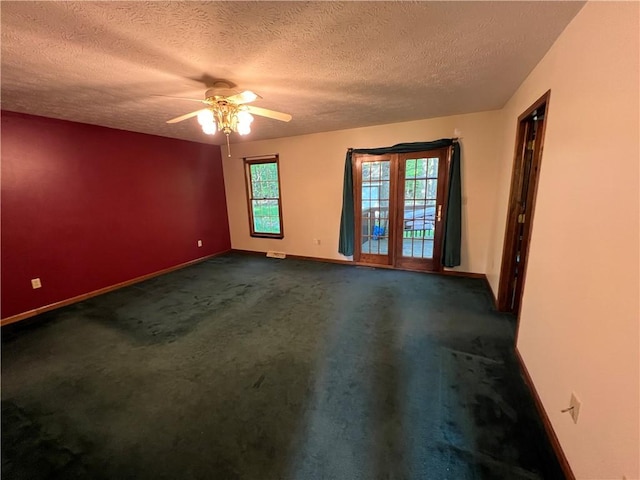 empty room with baseboards, plenty of natural light, ceiling fan, a textured ceiling, and dark colored carpet