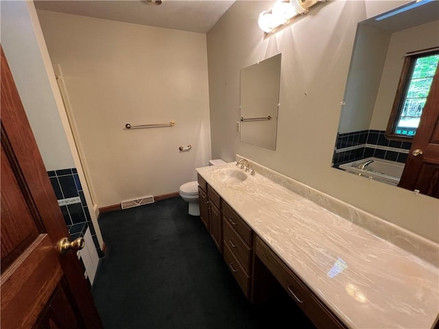 full bathroom featuring toilet, vanity, a tub, and baseboards