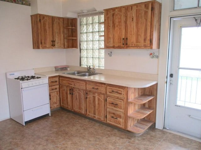 kitchen featuring white gas stove, open shelves, a sink, and light countertops