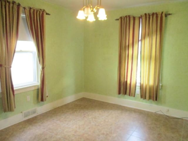 unfurnished room featuring a chandelier and baseboards