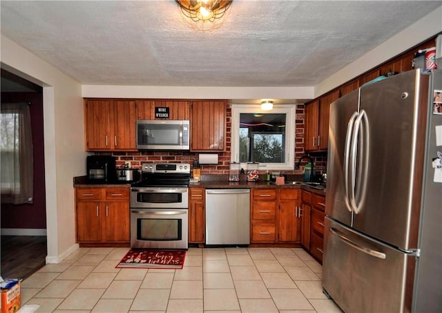 120 Scottsdale Dr, Moon/Crescent Twp, PA 15108 - kitchen featuring stainless steel appliances, dark countertops, decorative backsplash, brown cabinets, and a textured ceiling