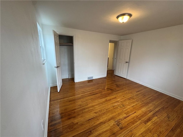 unfurnished bedroom featuring hardwood / wood-style floors, baseboards, and visible vents