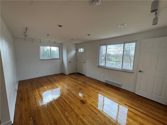interior space with baseboards, visible vents, light wood-style flooring, and track lighting