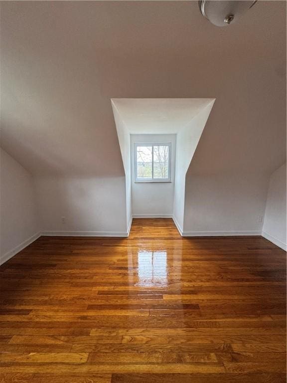 additional living space with baseboards, lofted ceiling, and wood finished floors