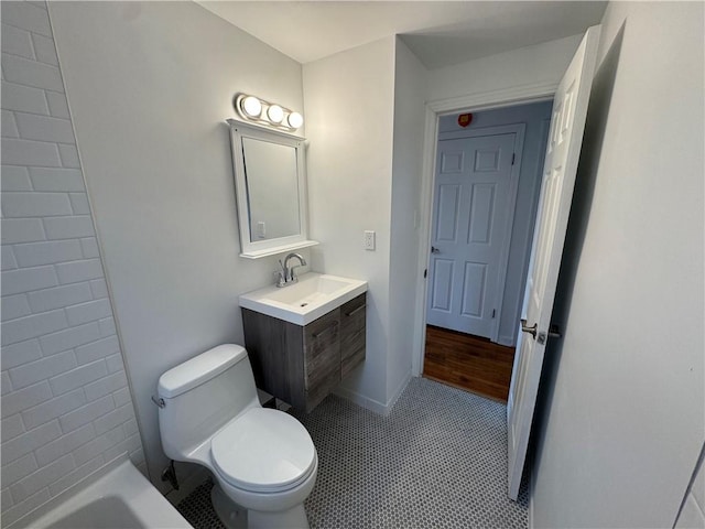 bathroom featuring toilet, vanity, baseboards, and a tub to relax in