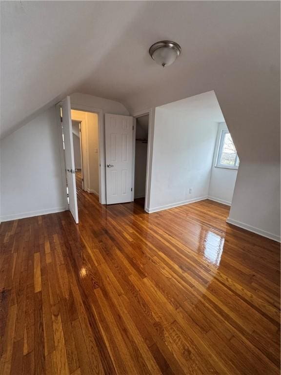 additional living space featuring baseboards, vaulted ceiling, and wood-type flooring