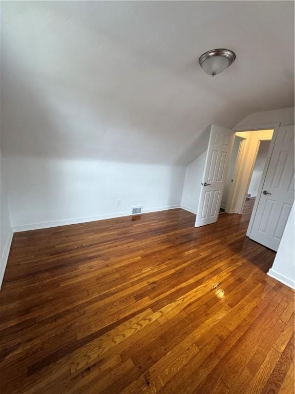 bonus room featuring baseboards, visible vents, vaulted ceiling, and hardwood / wood-style flooring