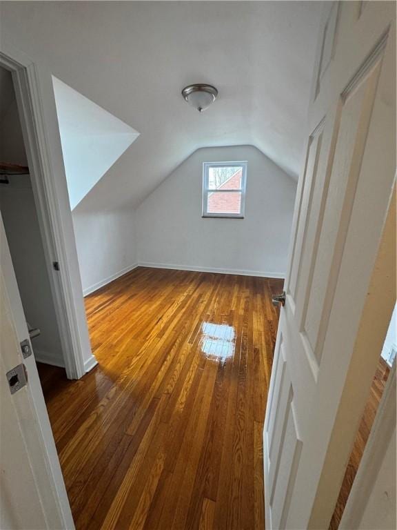 bonus room with baseboards, lofted ceiling, and hardwood / wood-style flooring