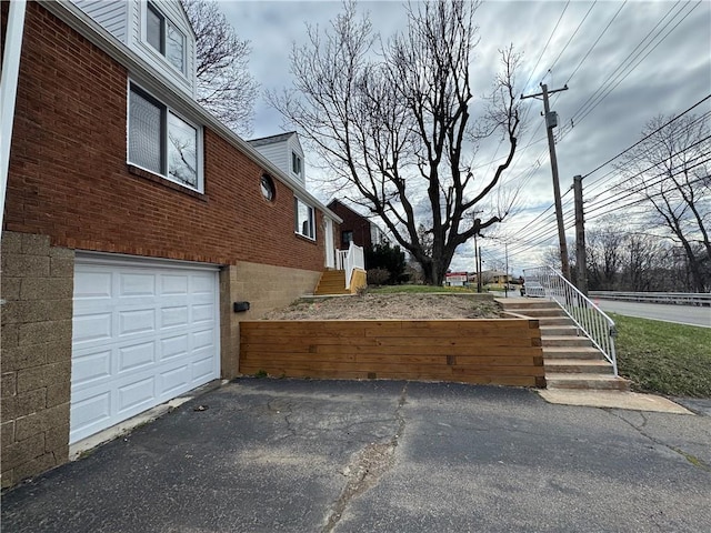 view of property exterior with brick siding, driveway, and a garage