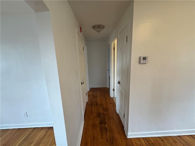 hall with baseboards and wood finished floors