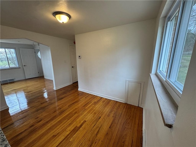 spare room with baseboards, visible vents, and wood finished floors