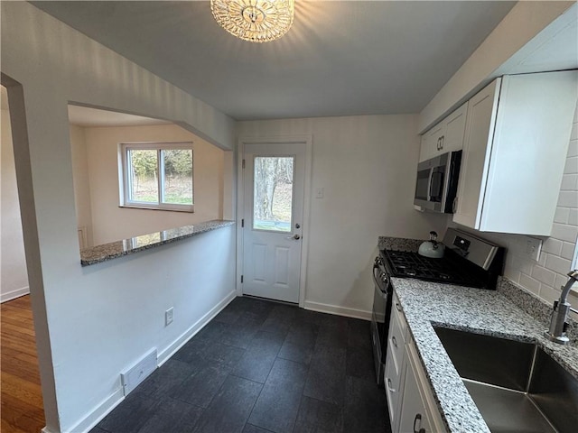 kitchen with a sink, white cabinetry, appliances with stainless steel finishes, and dark wood-style flooring