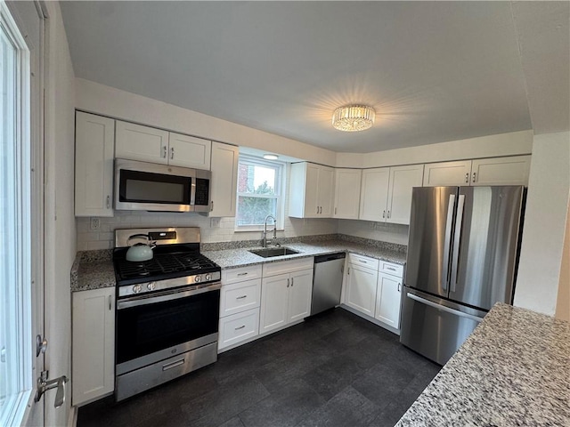kitchen featuring white cabinets, a sink, light stone countertops, and appliances with stainless steel finishes