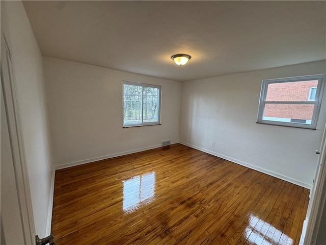 spare room with baseboards, visible vents, and hardwood / wood-style flooring