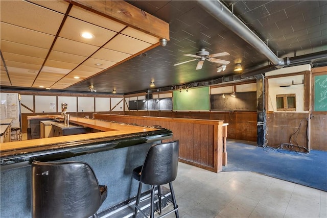bar featuring a wainscoted wall, tile patterned floors, wood walls, and a ceiling fan