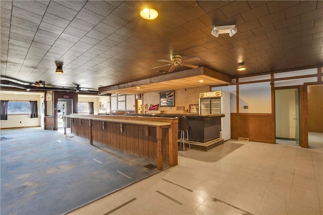 kitchen with ceiling fan, tile patterned floors, and wooden walls
