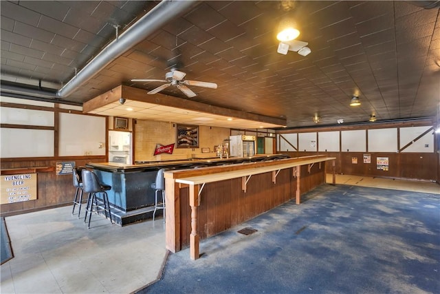 interior space featuring ceiling fan and wooden walls