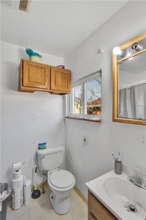 full bathroom featuring toilet, vanity, baseboards, and visible vents