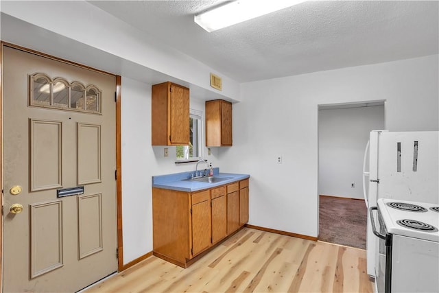 kitchen with white electric range oven, a sink, brown cabinetry, and light wood-type flooring