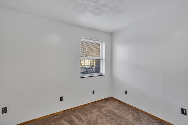 carpeted spare room featuring baseboards and a textured ceiling