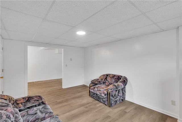 living area with baseboards, wood finished floors, and a paneled ceiling