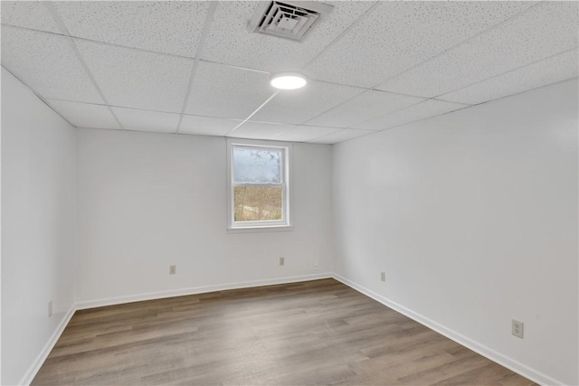 basement with baseboards, visible vents, a drop ceiling, and wood finished floors