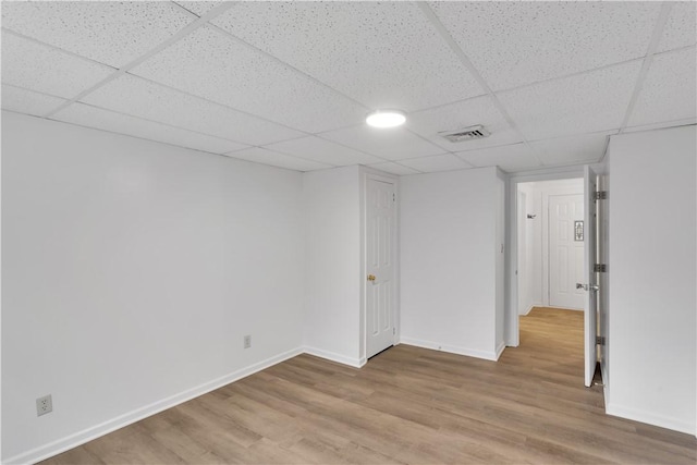 unfurnished room with a paneled ceiling, baseboards, light wood finished floors, and visible vents
