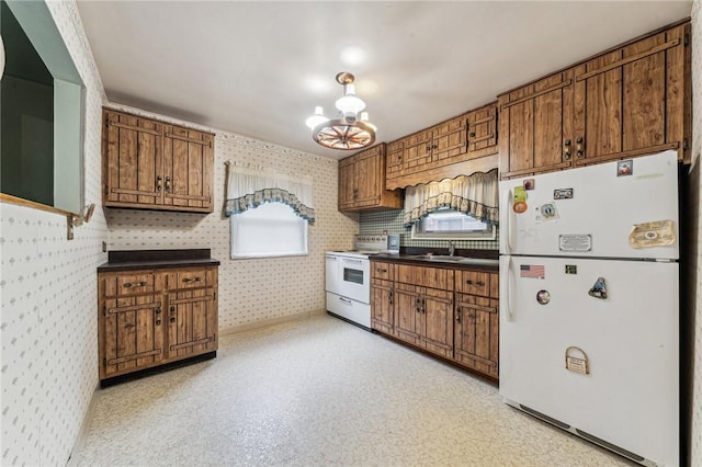 kitchen with wallpapered walls, dark countertops, brown cabinetry, and white appliances