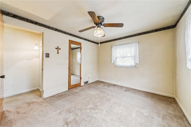 carpeted empty room featuring baseboards, visible vents, and a ceiling fan