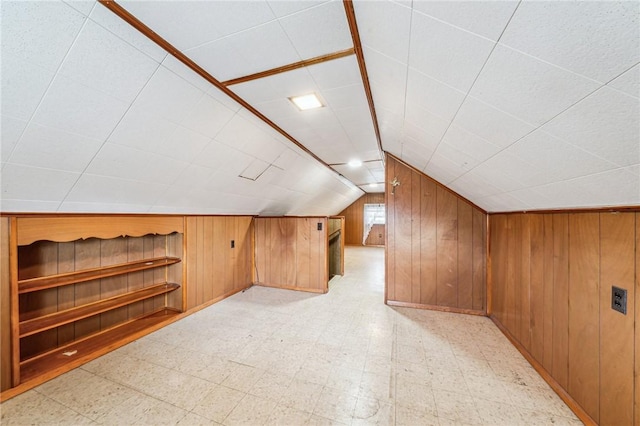 bonus room featuring lofted ceiling, wooden walls, and light floors