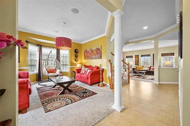 living room featuring crown molding, plenty of natural light, baseboards, and ornate columns